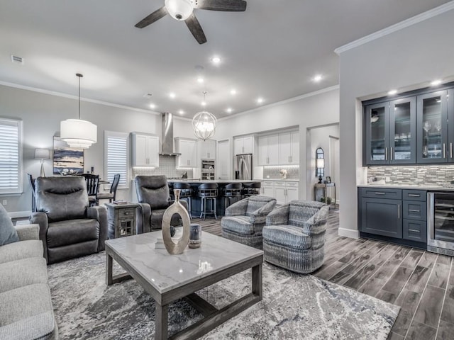 living room with beverage cooler, hardwood / wood-style floors, crown molding, ceiling fan, and a wealth of natural light