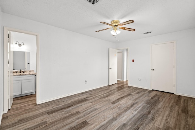 unfurnished bedroom with ceiling fan, dark hardwood / wood-style flooring, ensuite bath, and a textured ceiling