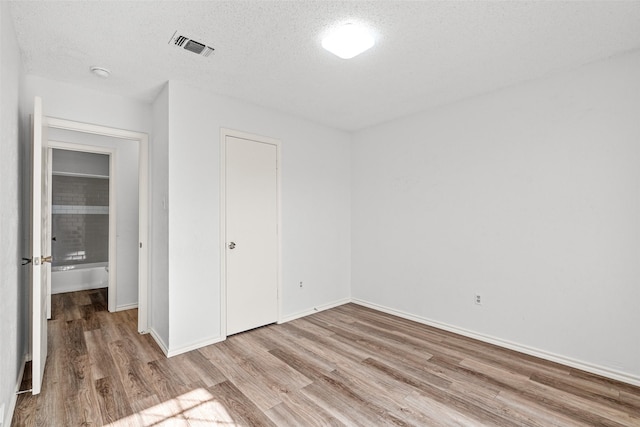 unfurnished bedroom featuring a textured ceiling, light hardwood / wood-style flooring, and a closet