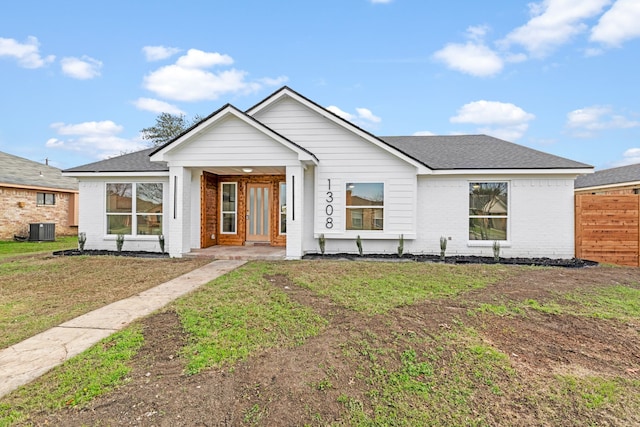 view of front of house with central AC and a front yard