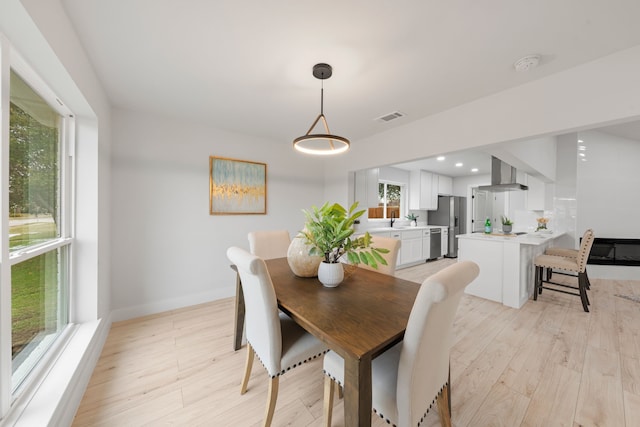 dining space with light hardwood / wood-style floors, sink, and plenty of natural light