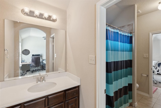 bathroom with tile patterned flooring, vaulted ceiling, toilet, vanity, and a textured ceiling