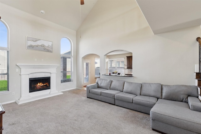 carpeted living room with high vaulted ceiling and ceiling fan