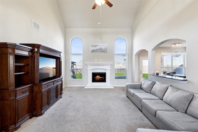 living room with ceiling fan, high vaulted ceiling, a healthy amount of sunlight, and light carpet