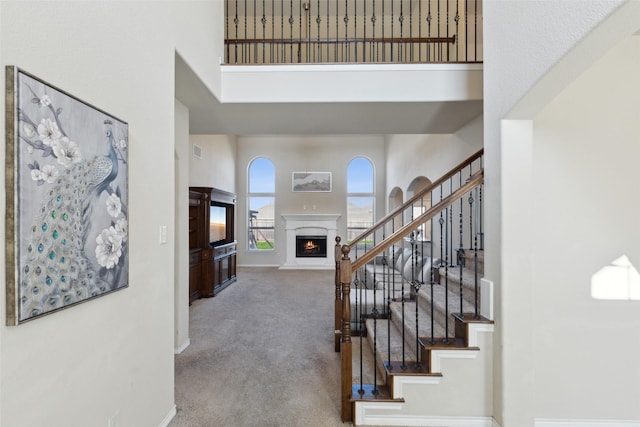 staircase featuring a high ceiling and carpet