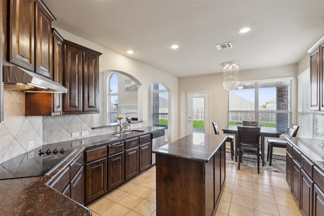 kitchen featuring sink, black electric stovetop, dark brown cabinets, and a center island