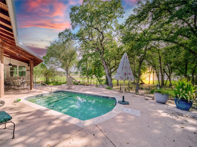 pool at dusk featuring a patio