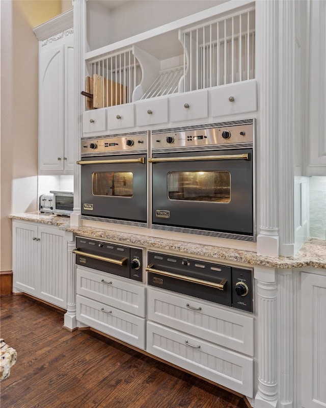 kitchen with light stone countertops, white cabinets, and dark wood-type flooring