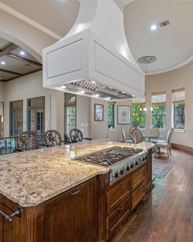 kitchen with stainless steel gas cooktop, plenty of natural light, light stone counters, and dark wood-type flooring