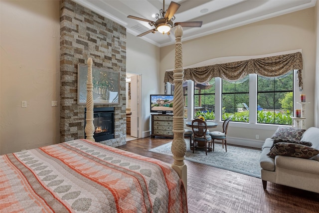 bedroom featuring a fireplace, ceiling fan, ornamental molding, and dark hardwood / wood-style floors