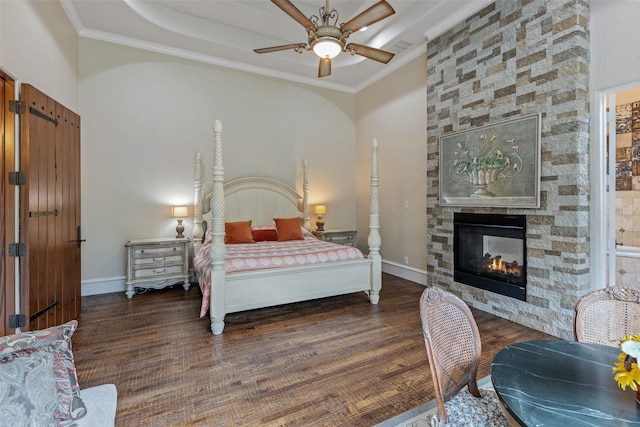 bedroom featuring a fireplace, dark wood-type flooring, ceiling fan, and ornamental molding