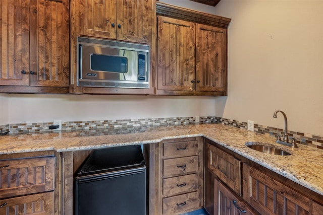 kitchen featuring sink, light stone countertops, and stainless steel microwave