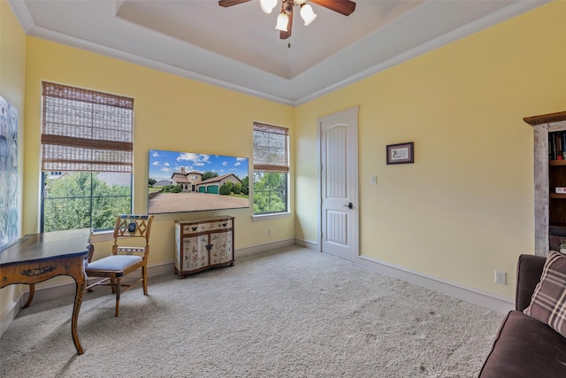 living area with a raised ceiling, carpet floors, ceiling fan, and ornamental molding