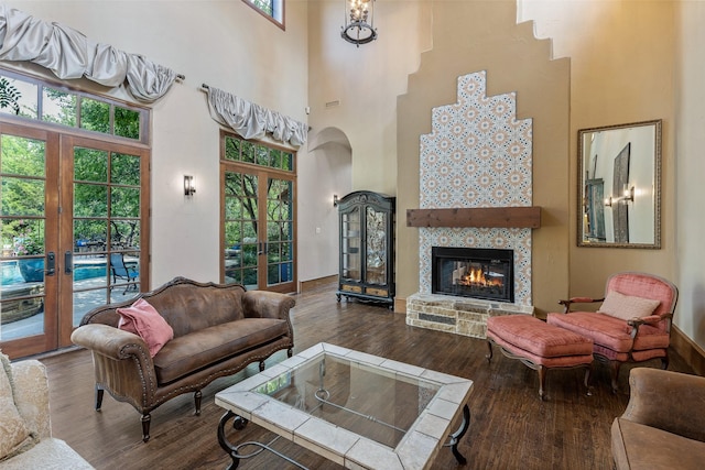 living room with a towering ceiling, french doors, dark hardwood / wood-style flooring, and a healthy amount of sunlight