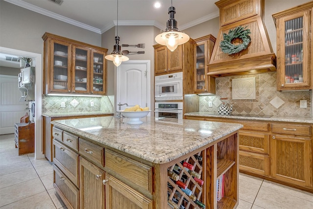 kitchen featuring a center island, light tile patterned floors, black electric cooktop, hanging light fixtures, and crown molding