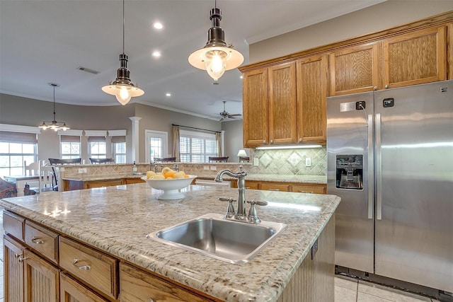 kitchen featuring a center island with sink, stainless steel refrigerator with ice dispenser, backsplash, ceiling fan, and sink