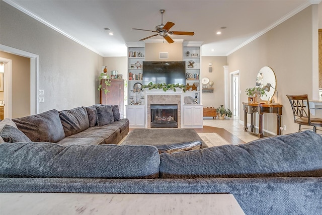 living room featuring light tile patterned floors, ceiling fan, built in shelves, and crown molding