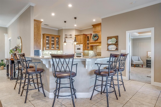 kitchen featuring kitchen peninsula, light colored carpet, light stone countertops, and a breakfast bar area