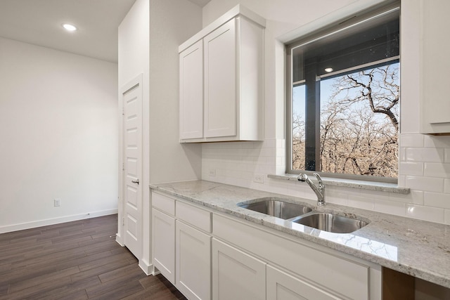 kitchen with white cabinetry, sink, light stone counters, and decorative backsplash