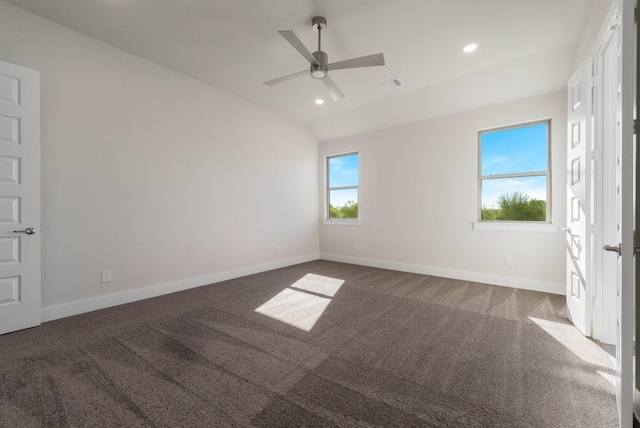 empty room featuring lofted ceiling, ceiling fan, and dark carpet