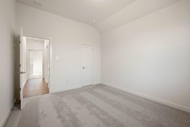 unfurnished bedroom featuring lofted ceiling and light colored carpet