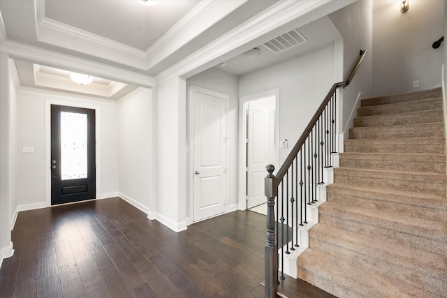 foyer entrance with a raised ceiling, dark wood-type flooring, and ornamental molding