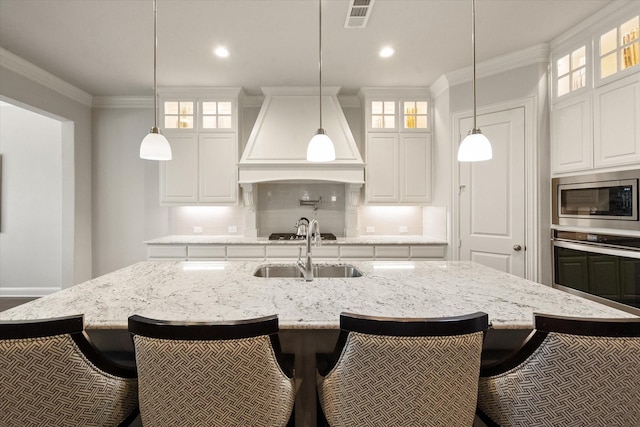 kitchen with a spacious island, white cabinetry, stainless steel appliances, premium range hood, and a breakfast bar area