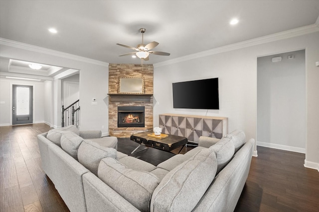 living room featuring dark hardwood / wood-style floors, crown molding, and a stone fireplace