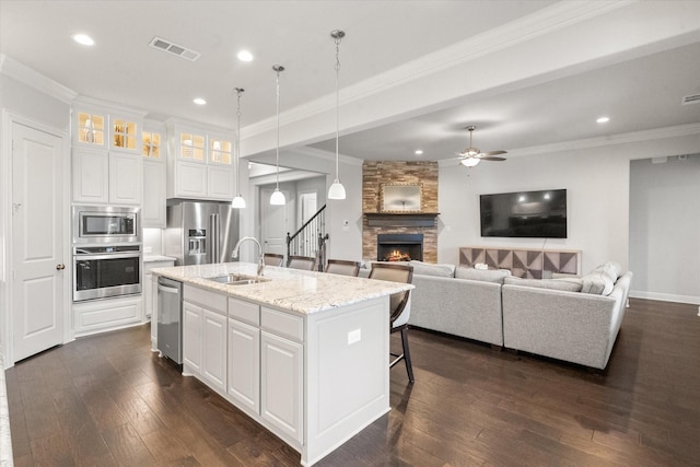 kitchen featuring a center island with sink, sink, appliances with stainless steel finishes, white cabinets, and light stone counters