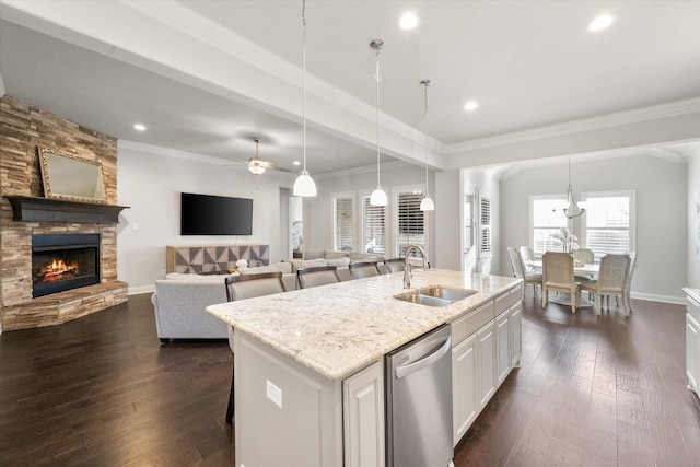 kitchen with white cabinetry, an island with sink, hanging light fixtures, stainless steel dishwasher, and sink