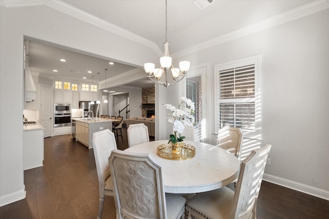 dining room featuring a fireplace, dark hardwood / wood-style flooring, an inviting chandelier, and crown molding