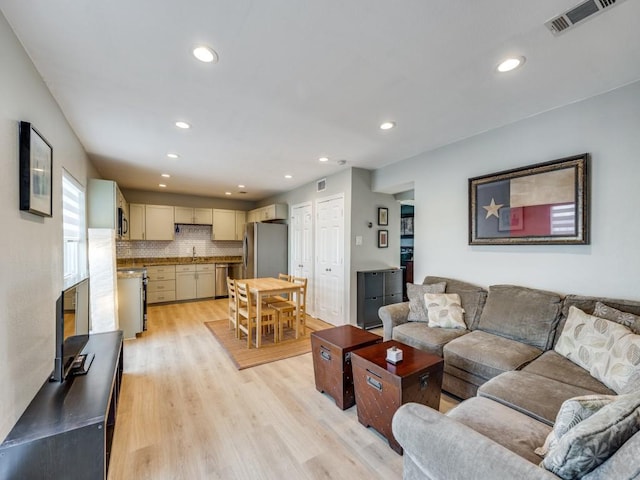 living room with light hardwood / wood-style floors and sink