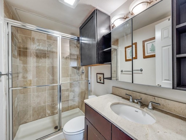 bathroom featuring toilet, a shower with shower door, and vanity