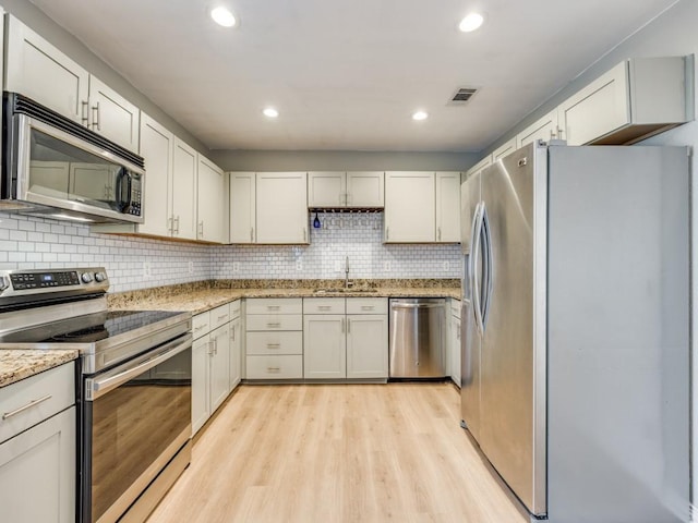 kitchen with appliances with stainless steel finishes, light hardwood / wood-style flooring, and white cabinets