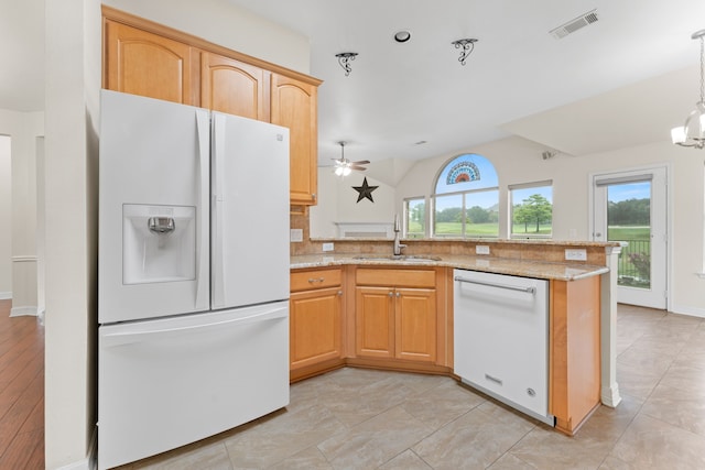 kitchen featuring white appliances, kitchen peninsula, light stone counters, sink, and ceiling fan with notable chandelier