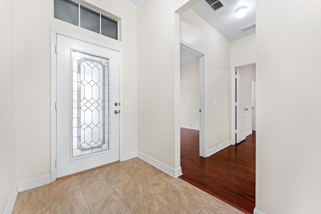 foyer entrance with ornamental molding and light tile patterned flooring