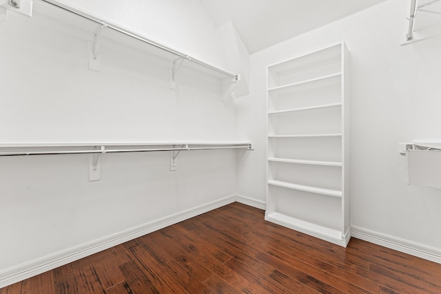 walk in closet with dark wood-type flooring and vaulted ceiling