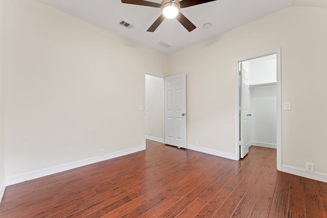 unfurnished bedroom with a closet, ceiling fan, a spacious closet, and dark hardwood / wood-style flooring