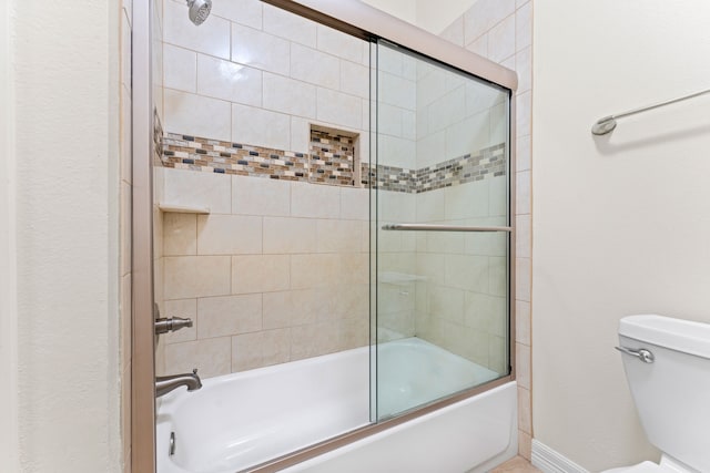 bathroom featuring toilet and combined bath / shower with glass door