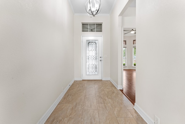 foyer featuring ceiling fan with notable chandelier, light wood-type flooring, and ornamental molding