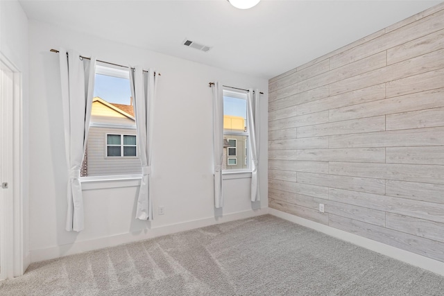 carpeted spare room with wooden walls