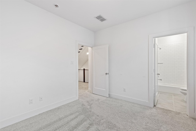 unfurnished bedroom with connected bathroom and light colored carpet