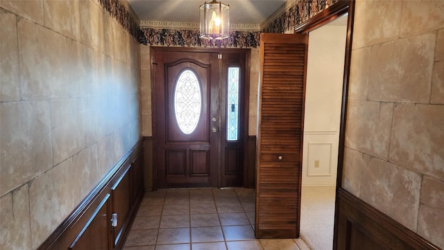 entryway with light tile patterned flooring and ornamental molding