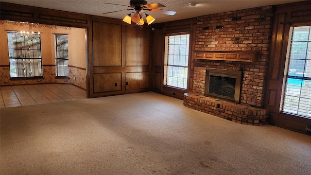 unfurnished living room featuring a brick fireplace, a textured ceiling, ceiling fan, and light colored carpet