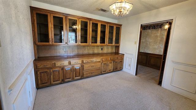 kitchen with light colored carpet, a notable chandelier, and a textured ceiling