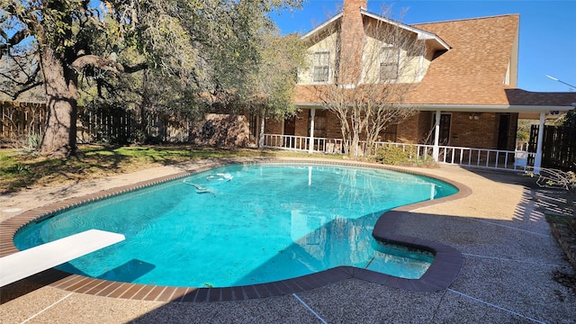 view of pool with a diving board and a patio area