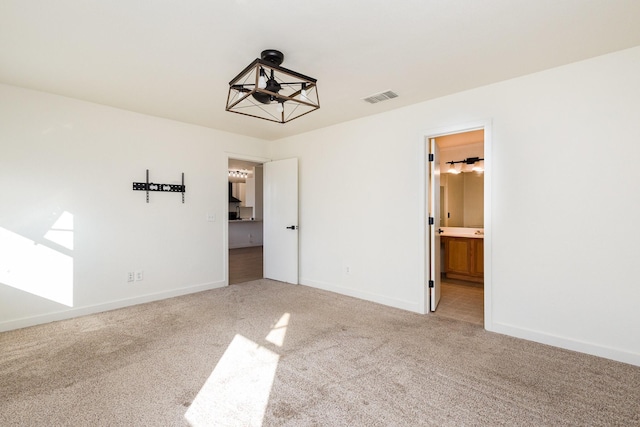 unfurnished bedroom featuring ensuite bath and carpet