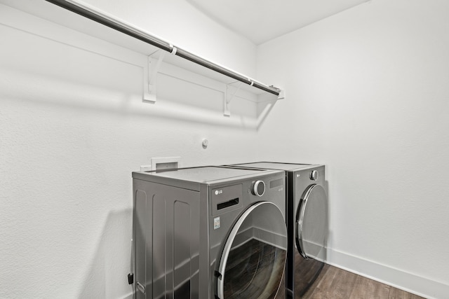 clothes washing area with dark hardwood / wood-style flooring and washing machine and dryer