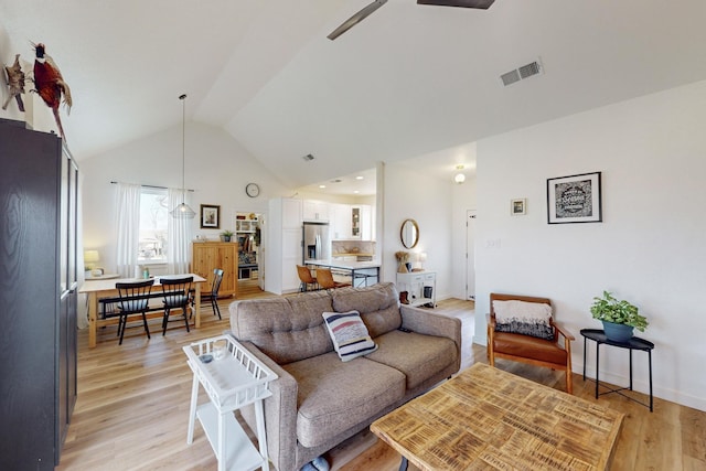 living room with lofted ceiling, ceiling fan, and light hardwood / wood-style flooring