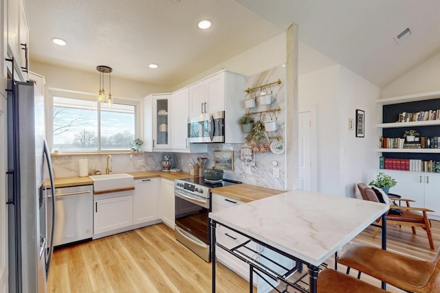 kitchen featuring stainless steel appliances, decorative light fixtures, white cabinets, decorative backsplash, and wooden counters